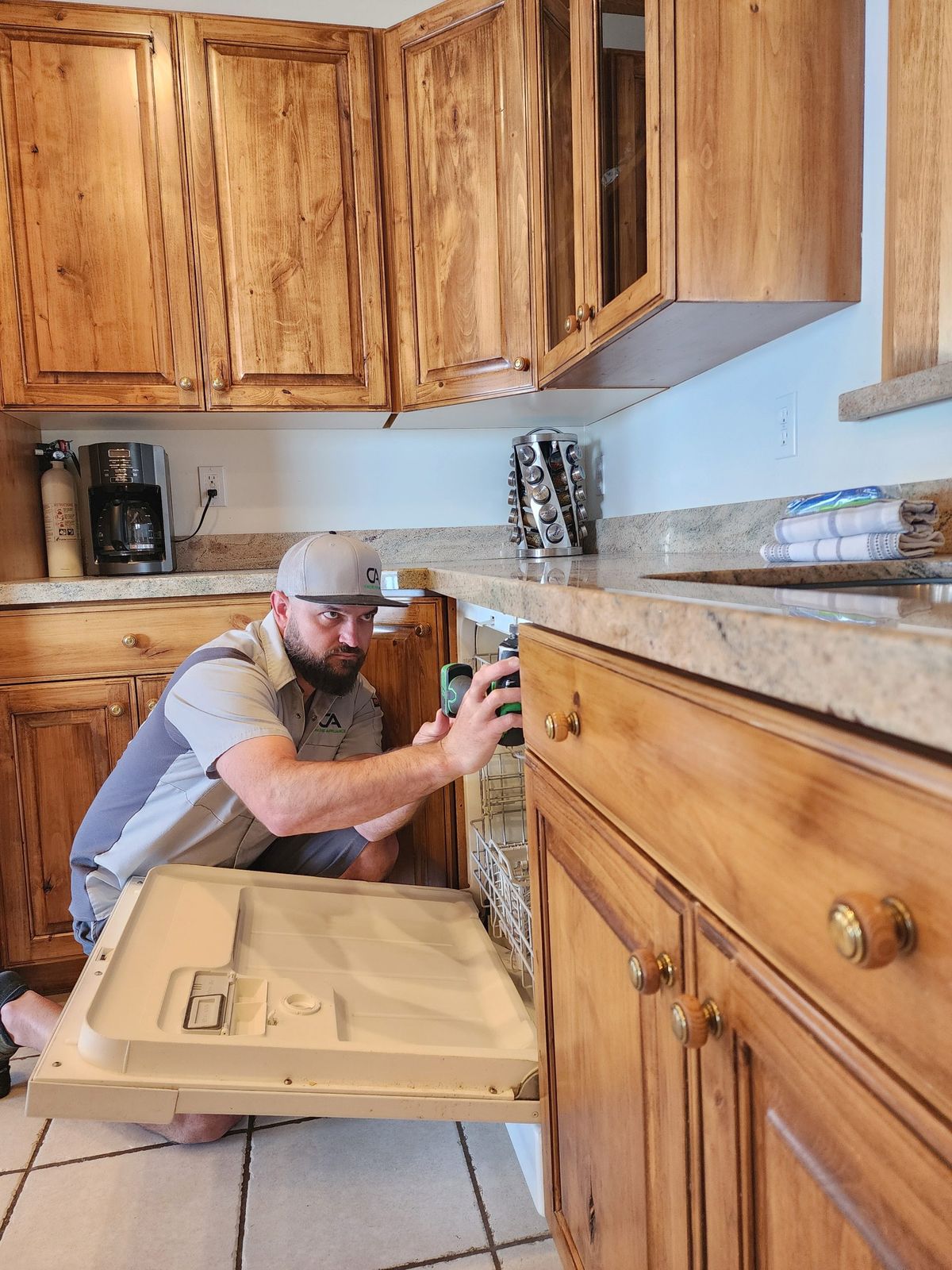 Cache Appliance technician working on a built-in dishwasher in a Cache Valley kitchen