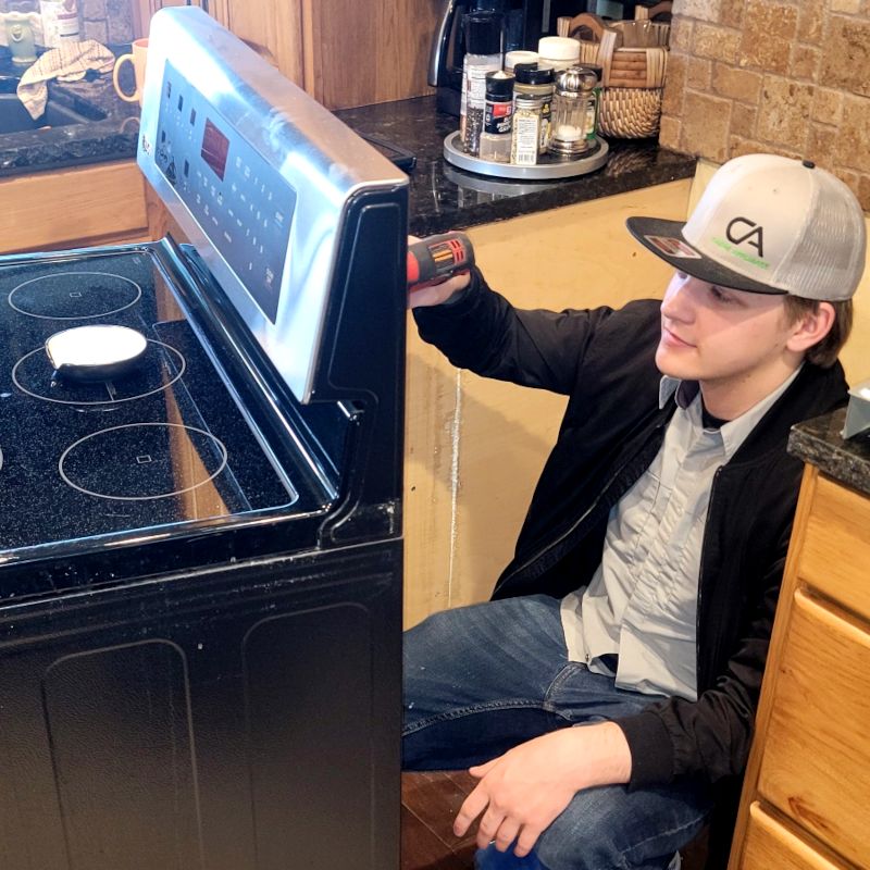 Cache Appliance technician checking the controls on a glass-top electric range