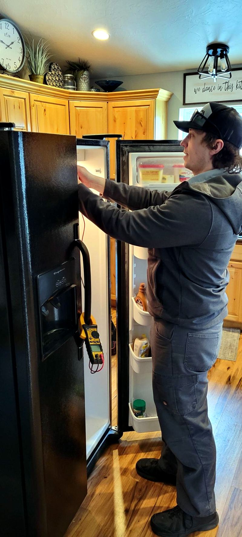 Cache Appliance technician diagnosing a side-by-side refrigerator with a clamp meter